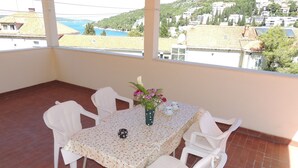 Un balcón con mesa y sillas, un florero con flores y vistas a edificios y una masa de agua.
