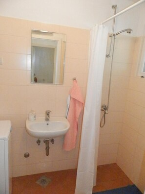 A bathroom with a sink, mirror, shower, and a pink towel hanging on the wall. - Villa Hortenzia (Dubrovnik)