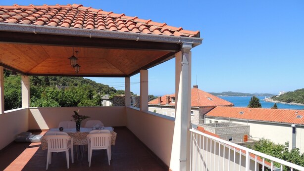 Un espacio al aire libre cubierto con una mesa y sillas, con vistas a un paisaje costero.