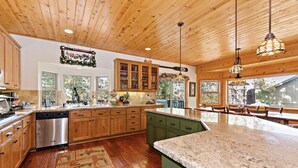 Una cocina amplia con armarios de madera, una isla grande y un comedor con vistas al exterior.