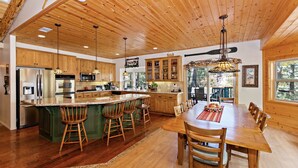 Una cocina amplia con armarios de madera, una isla central con taburetes de bar y un comedor con una mesa grande y sillas.
