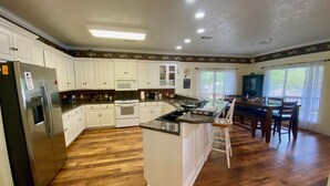A spacious kitchen with white cabinets, a stainless steel refrigerator, a microwave, and a stove.
