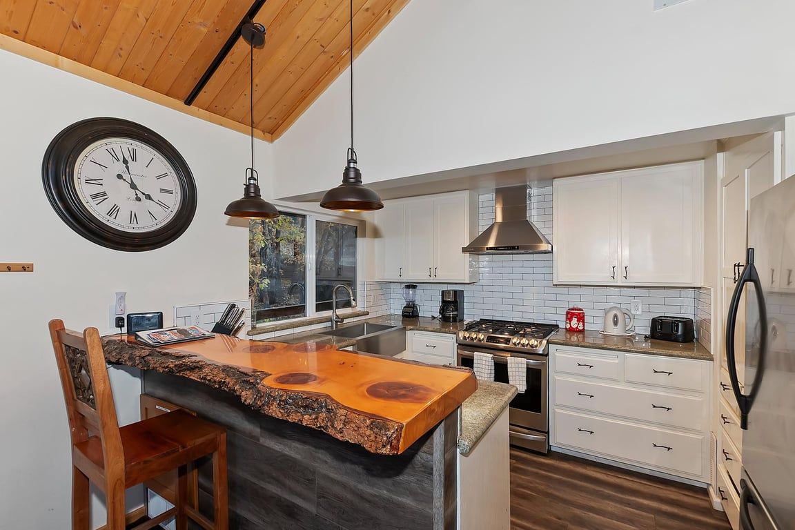 Una cucina moderna con isola centrale, soffitto in legno e mobili bianchi.