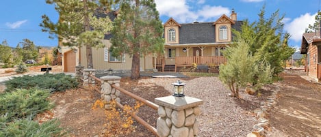 A two-story house with a stone fence, a front porch, and a driveway.