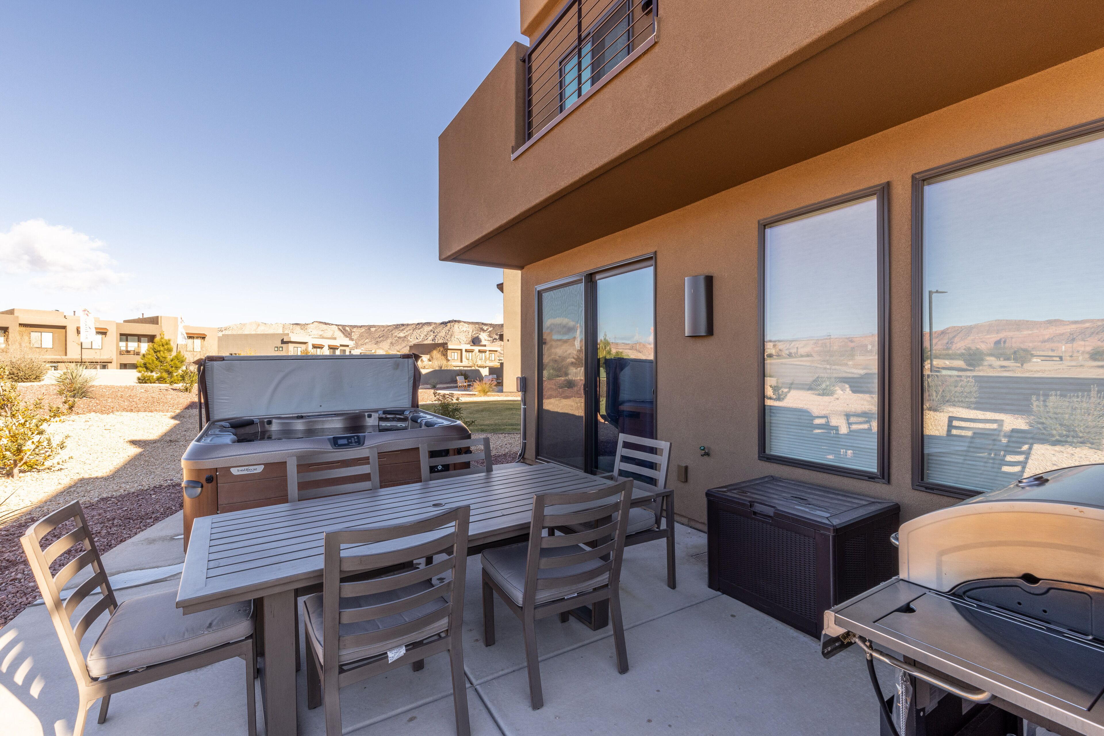 An outdoor patio with a barbecue grill, dining table, and chairs.