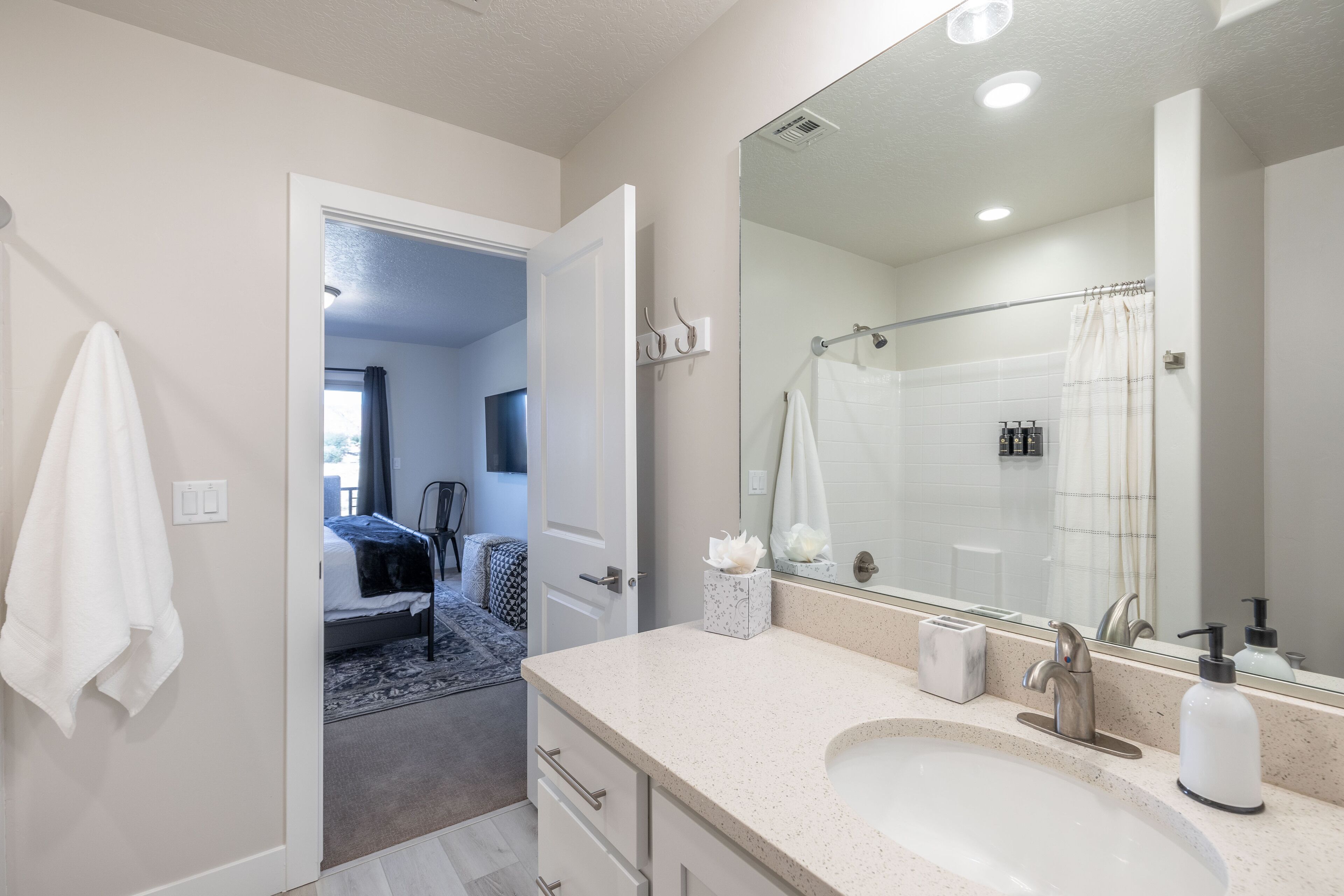 A modern bathroom with a large mirror, a sink, and a shower.