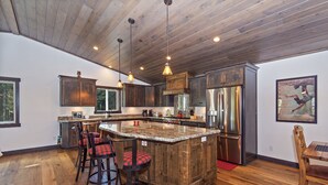 Una cocina moderna con una isla grande, suelo de madera y taburetes de bar.