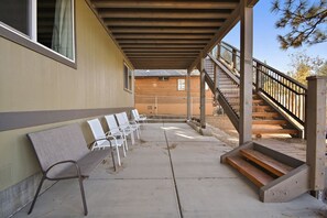 A covered outdoor seating area with chairs and a wooden staircase.