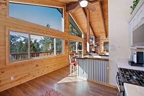 A spacious kitchen with wooden beams, large windows, and a view of the outdoors.