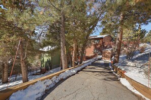 Un sendero cubierto de nieve flanqueado por árboles que conduce a un edificio con tejado rojo.
