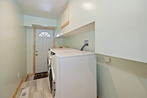 Un lavadero con lavadora y secadora, una puerta con panel de vidrio decorativo y una pequeña mesa.