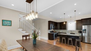 A modern kitchen with dark wooden cabinets, stainless steel appliances, and a central island with stools. - 🐟Bikes-Walk 2 Beach-Calm Breeze Cottage (Santa Rosa Beach)