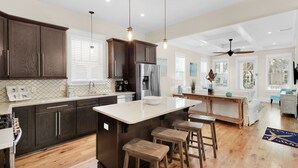 A modern kitchen with dark wood cabinets, a central island with stools, and pendant lighting. - 🐟Bikes-Walk 2 Beach-Calm Breeze Cottage (Santa Rosa Beach)