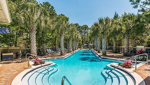A swimming pool with a curved design, surrounded by palm trees and lounge chairs. - 🐟Bikes-Walk 2 Beach-Calm Breeze Cottage (Santa Rosa Beach)