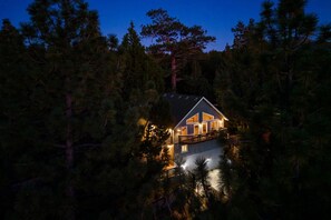 Une cabane à deux étages, entourée d’une forêt dense.