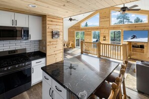 A modern kitchen with a black countertop, white cabinets, and a built-in oven. - Mooncrest Manor by Destination Big Bear : Expansive Mountain Views! Large Family Spaces! Pet Friendly! Game Room! (Big Bear Lake)