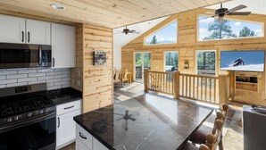 Una cucina moderna con un piano di lavoro nero, mobili bianchi e un'ampia finestra che si affaccia su un paesaggio innevato.