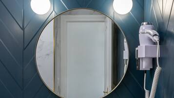 A bathroom with a marble sink, gold fixtures, and a hairdryer mounted on the wall.