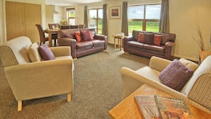A spacious living room with two leather sofas, a wooden coffee table, and a dining area with a table and chairs. - Drumlanrig Lodge with hot tub and views of Loch Lomond (Loch Lomond)