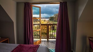 Ein Schlafzimmer mit großem Fenster, einem Bett, einem Nachttisch und Blick auf eine Terrasse und einen Garten.