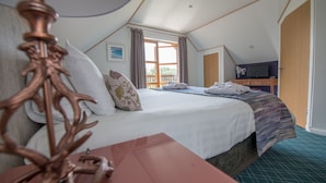 A bedroom with a bed, a wooden desk, a television, and a window with curtains. - Cawdor  Diamond  Lodge with hot tub and Loch views (Balmaha)