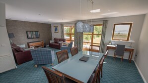 A spacious living area with a dining table, multiple chairs, a sofa, and a television. - Cawdor  Diamond  Lodge with hot tub and Loch views (Balmaha)