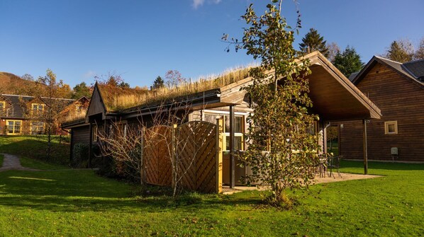 A wooden cabin with a sloped roof, a covered porch, and a small garden area.