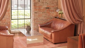 Ein Zimmer mit Ledersofa, Glastisch und Backsteinwand.