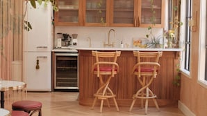 Eine Küche mit Holzschränken, einem eingebauten Backofen und zwei Barhocker mit roten Kissen.