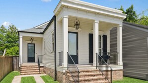 A two-story house with a front porch, a front door, and a staircase leading to the entrance.