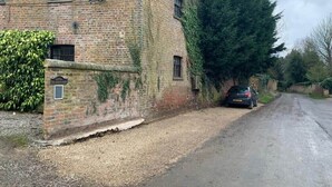 Ein Backsteinhaus mit Kiesweg und einem geparkten Auto.