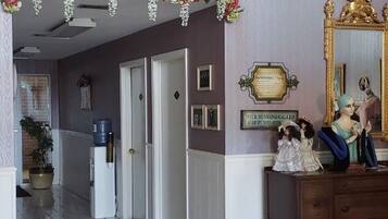 A hallway with a tiled floor, a framed picture on the wall, a mirror, and a dresser with decorative items.
