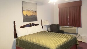 Une chambre d’hôtel avec un lit, une chaise, une lampe, un climatiseur et un tableau au mur.