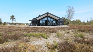 A modern building with large glass windows, a covered outdoor seating area, and a natural landscape surrounding it. - Holiday Home in LÃ¦sÃ¸ (Læsø)