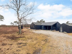 A building with a gravel driveway and a tree in the foreground.
