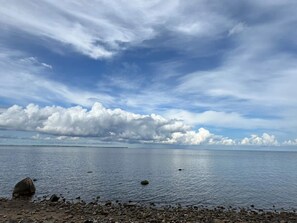 A calm body of water with a rocky shoreline and a partly cloudy sky.