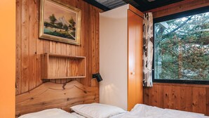 A wooden room with a bed, a shelf, and a painting on the wall. - 4 Person Holiday Home in Fano (Fano)