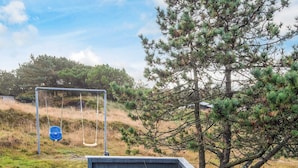 A swing set in a grassy area with a small shed nearby. - 4 Person Holiday Home in Fano (Fano)