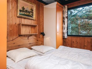 A wooden room with a bed, a shelf, and a window with curtains. - 4 Person Holiday Home in Fano (Fano)