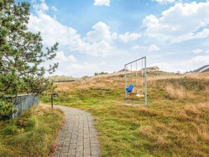 A pathway leading to a playground with a swing set and a small shelter. - 4 Person Holiday Home in Fano (Fano)