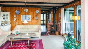A cozy living room with a sofa, a coffee table, a fireplace, and a large window. - 4 Person Holiday Home in Fano (Fano)