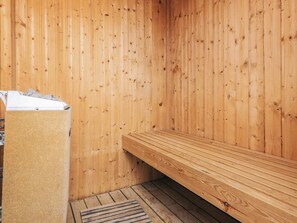 Uma sauna de madeira com um banco e um porta-toalhas.