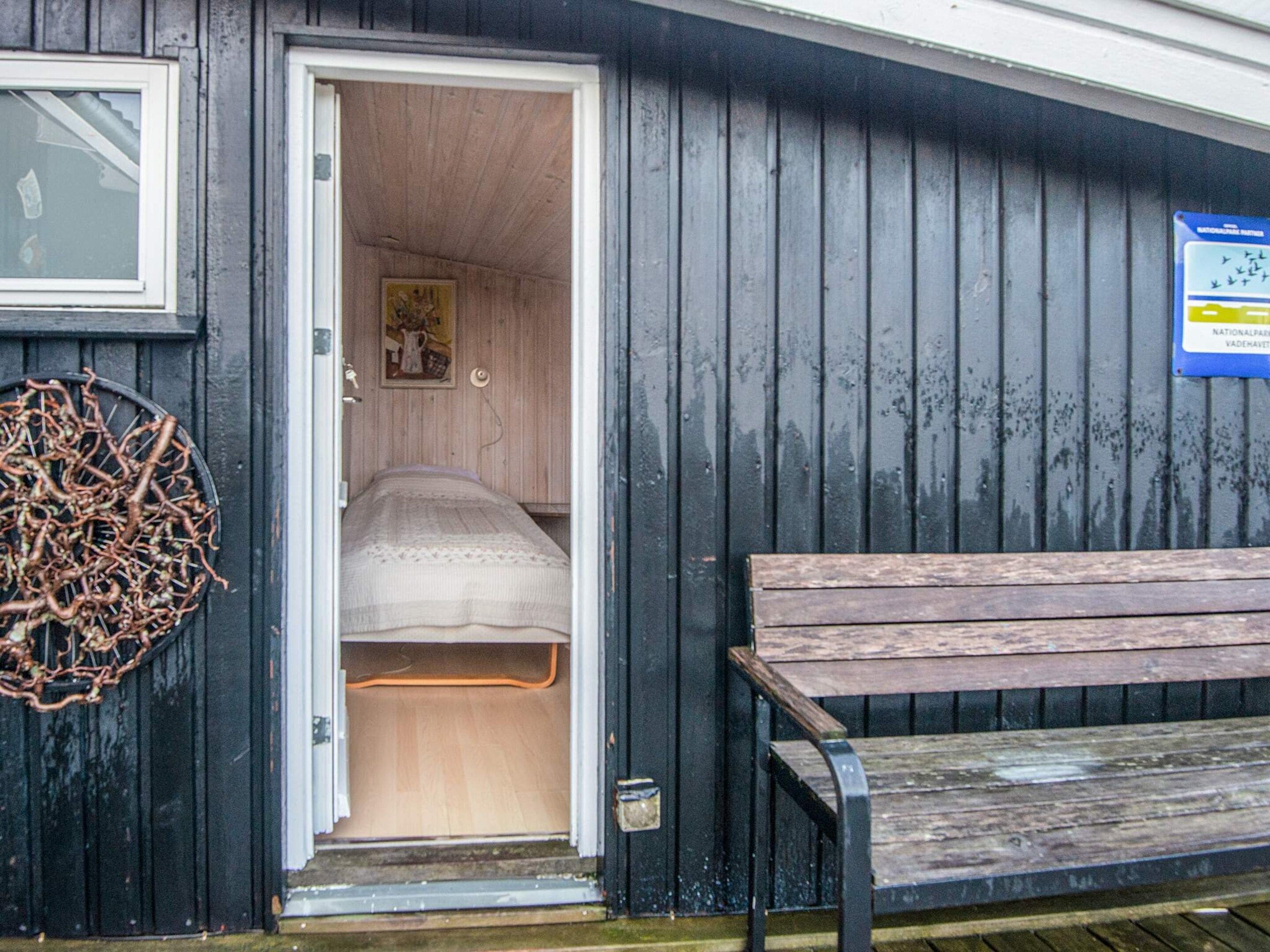 A small, compact room with a bed and a bench outside.