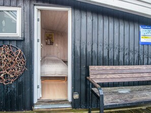 Ein kleines, gemütliches Zimmer mit einem Bett und einer Bank draußen.