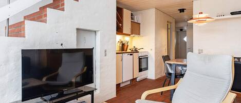A modern interior with a TV, seating area, kitchen, and staircase.