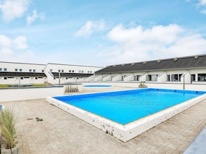 Piscina com um prédio branco ao fundo.