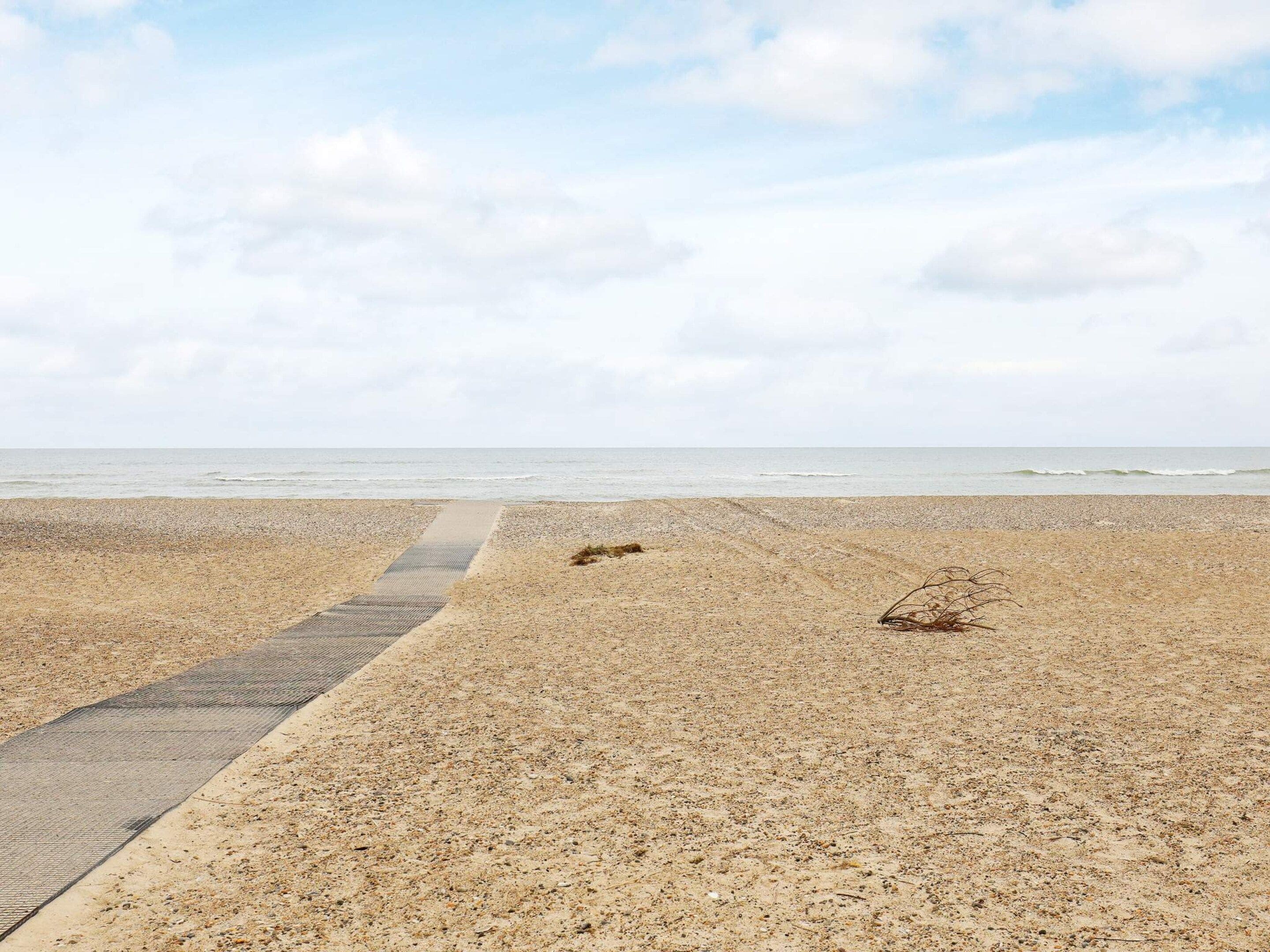 A beach with a paved walkway leading to the water.