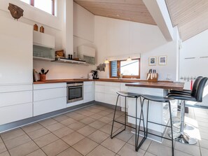 A modern kitchen with white cabinets, a wooden countertop, and a large window. - 5 Star Holiday Home in Fano (Fano)