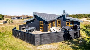 A modern wooden house with a patio area, large windows, and a sloped roof. - 5 Star Holiday Home in Fano (Fano)