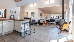 A spacious living area with a kitchen, dining area, and seating space. There are two windows providing natural light, a fireplace, and a tiled floor. - 5 Star Holiday Home in Fano (Fano)